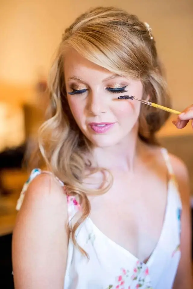 Woman with brush applying makeup, eyes closed.