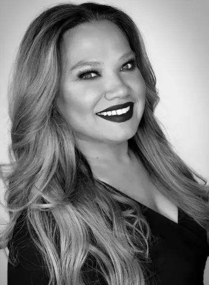 Smiling woman with long hair in black and white.