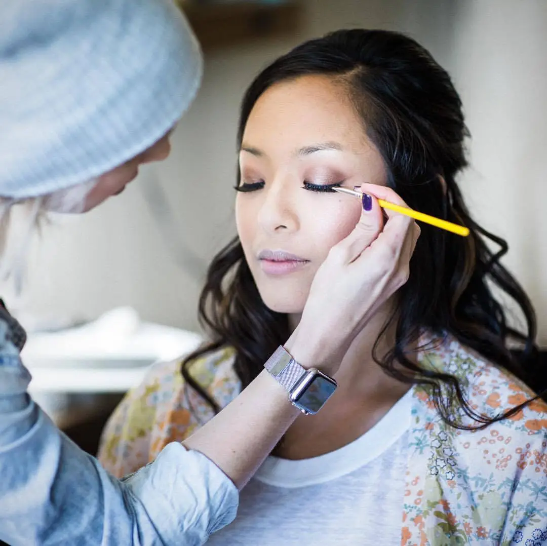 Makeup artist applying eyeshadow on woman