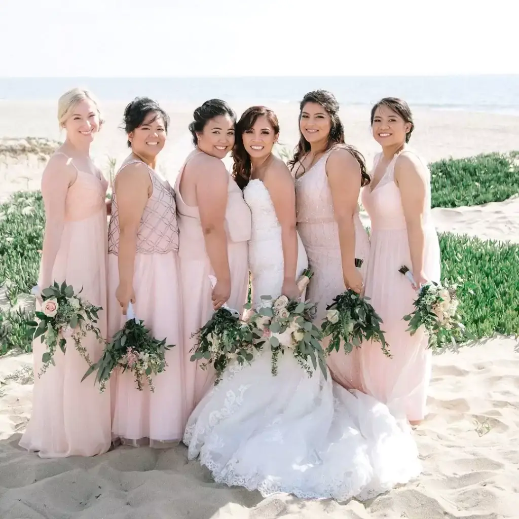 Bridesmaids in pink dresses on a beach.